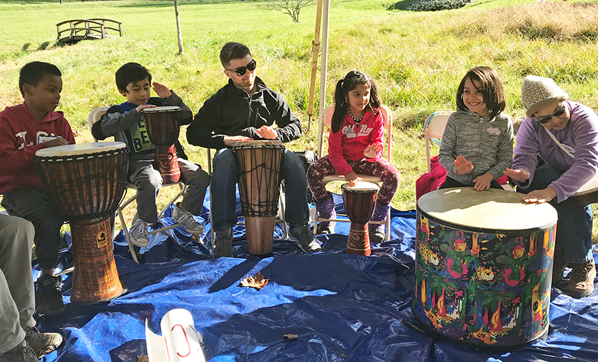 adults and children outside playing instruments