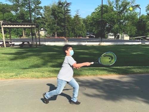 child holding tennis racket to hit tennis ball