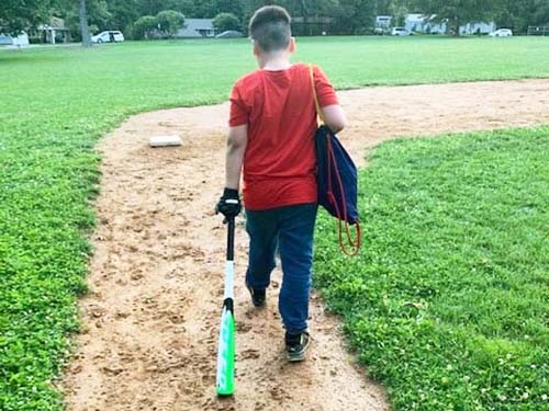 child walking and wearing bag and holding baseball bat