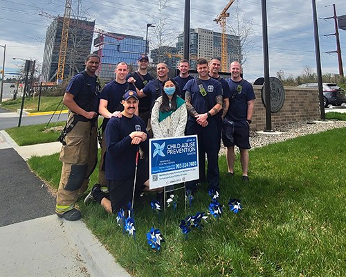 Firefighters posing with girl scout and pinwheel garden