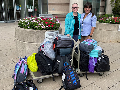 two women standing in front of backpacks