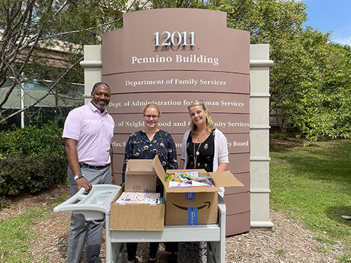 three people standing with school supplies