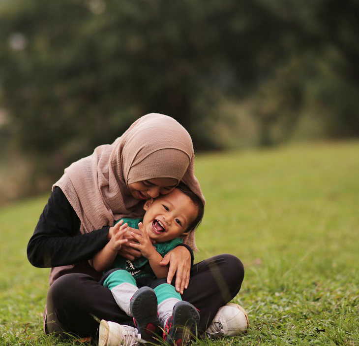 parent and child sitting outside on grass