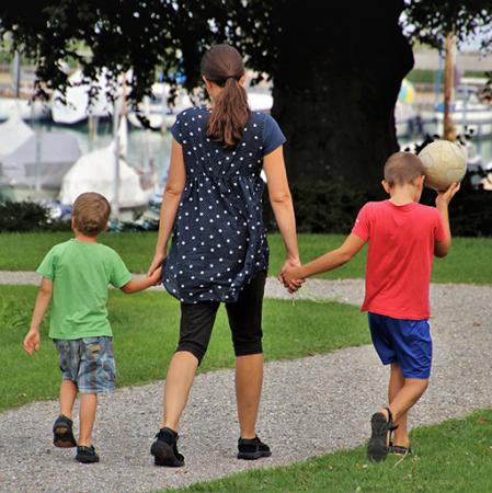 parent and two children holding hands and walking outside