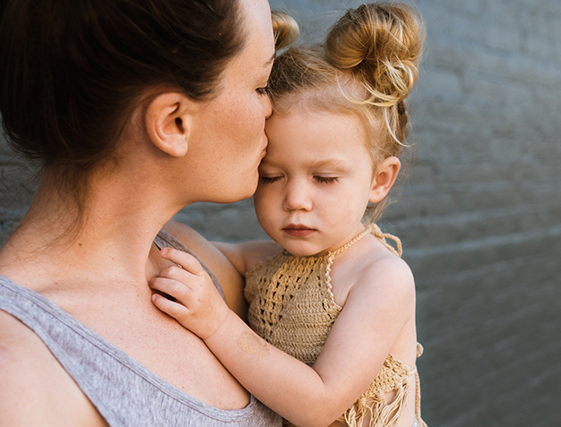 parent holding child in arms kissing forehead