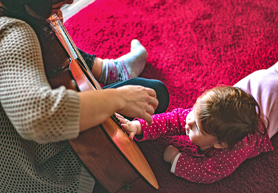 parent playing guitar for baby