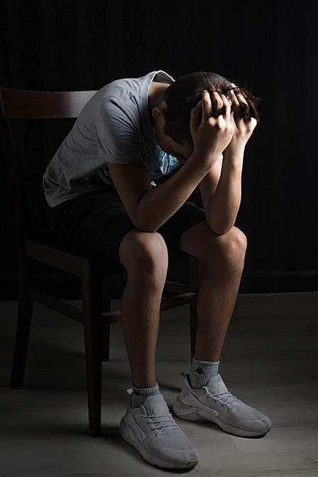 teen holding head in hands