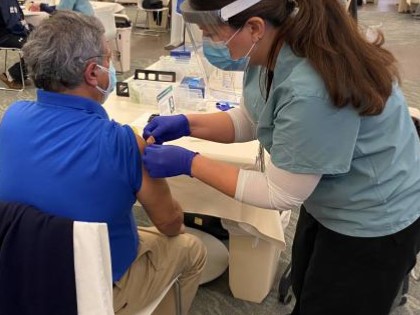 person administering vaccine shot to patient