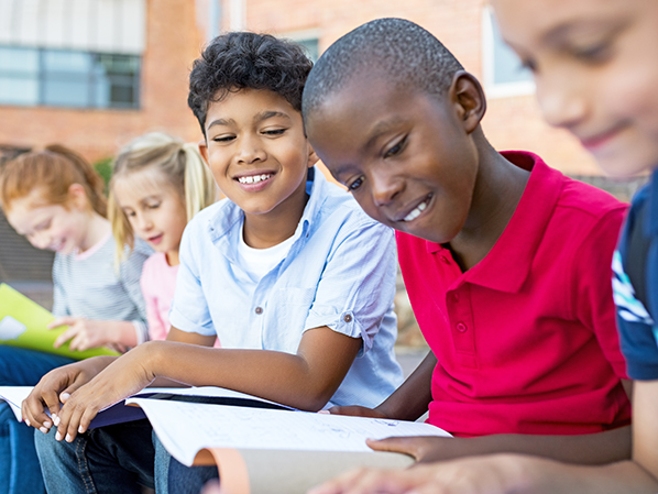 five children sitting outside doing homework