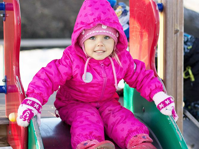 toddler wearing coat outside on slide