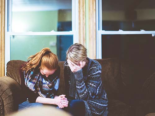 two people sad sitting side by side on sofa