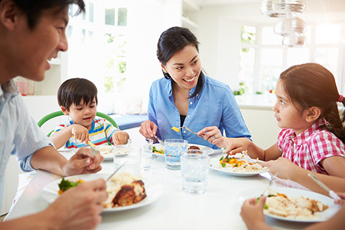 Two adults eating with children