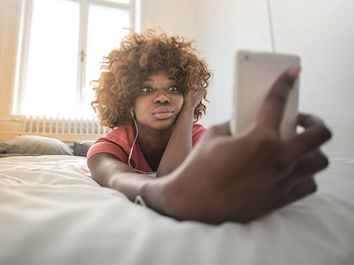 teen girl taking selfie on bed