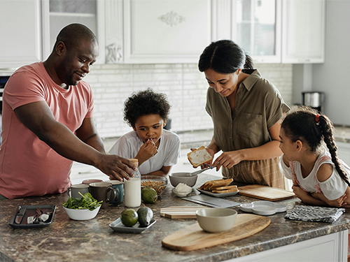 man and woman with two children making breakfast