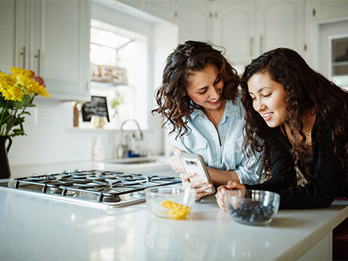 woman smiling at daughter with cell phone