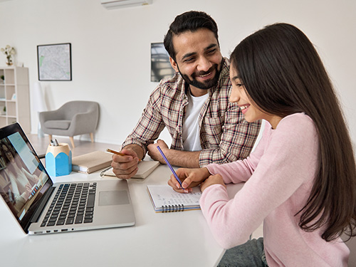 father and teen daughter in front of laptop