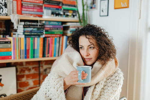 woman wrapped in blanket with mug in hand