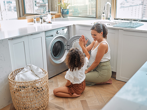 mother giving daughter high-five on laundry room floor