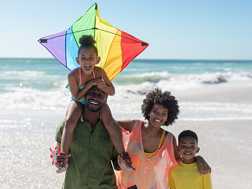 smiling family on beach with kite