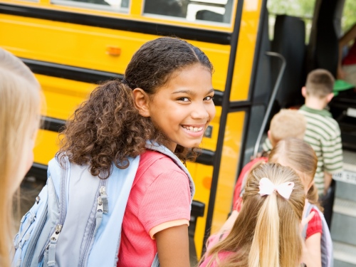 smiling girl waiting in line to board bus
