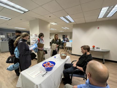 Students talking to staff sitting at table.