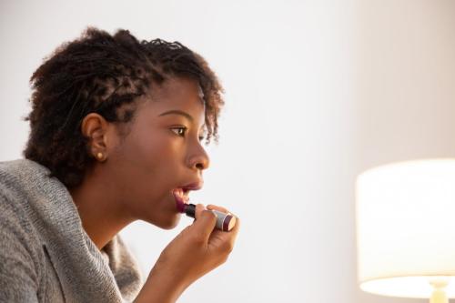 woman putting on lipstick