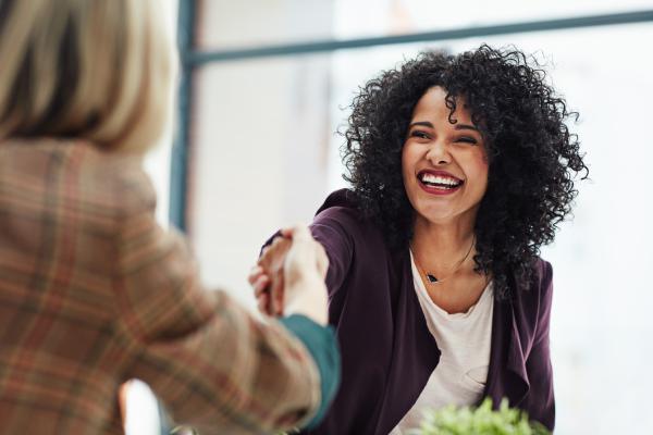 woman smiling while shaking a hand