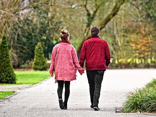 two people holding hands walking down path