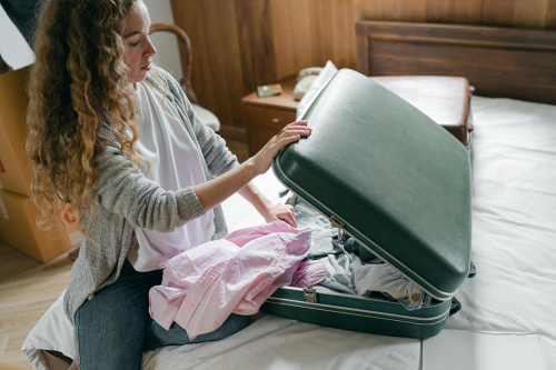 woman packing green suitcase