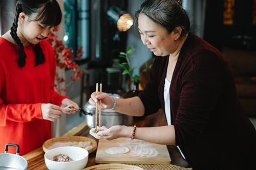 teen and older woman cooking in kitchen
