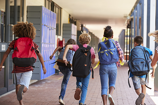 youth wearing backpacks and running down hallway