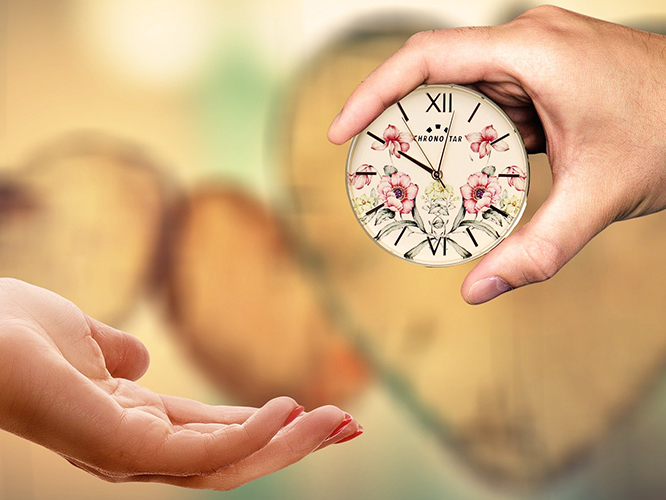 one hand giving clock to another hand