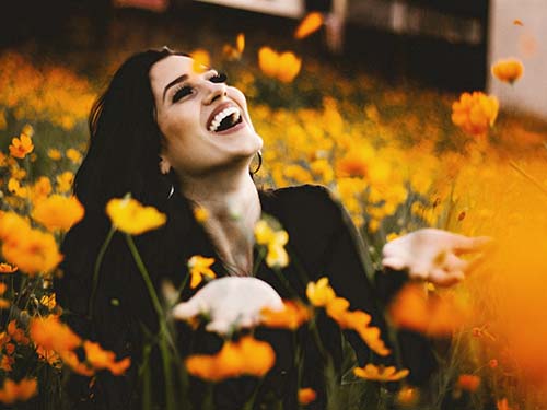 person sitting and smiling in field of flowers