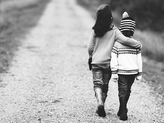 two young children walking on gravel road