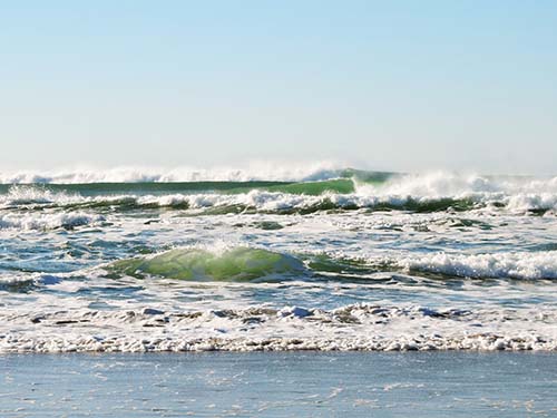 multiple ocean waves crashing onto beach