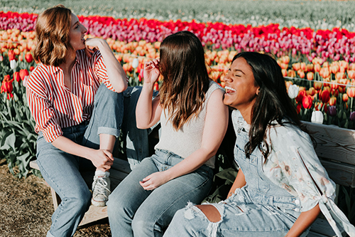 group of women laughing on bench in tulip field