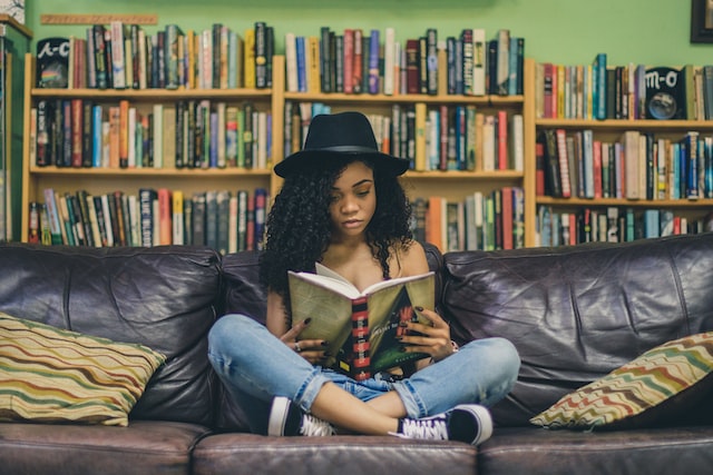 woman sitting on leather couch reading a book