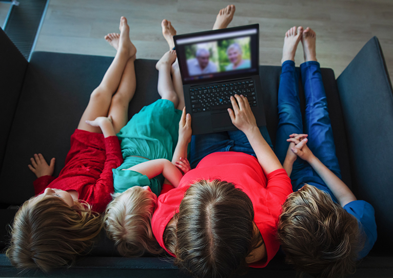 three children using laptop for video chat with older adults