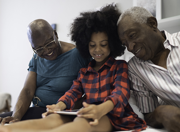 two older adults with young child looking at book together