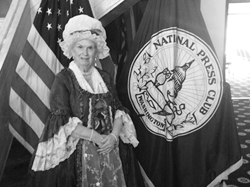 Bonnie dressed as Martha in front of U.S. and National Press Club flags