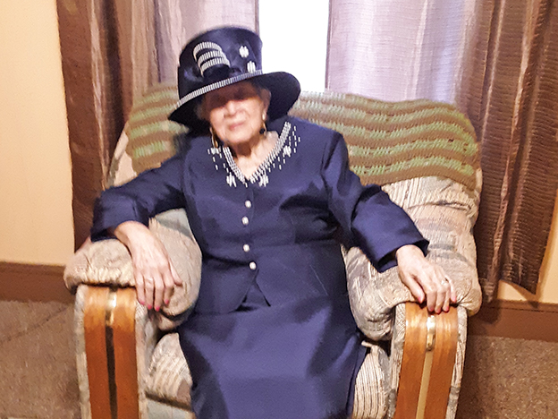 Josephine Joyce wearing dressy hat and sitting in armchair