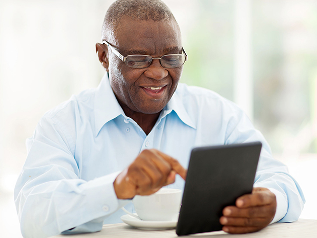 older adult sitting at table using tablet