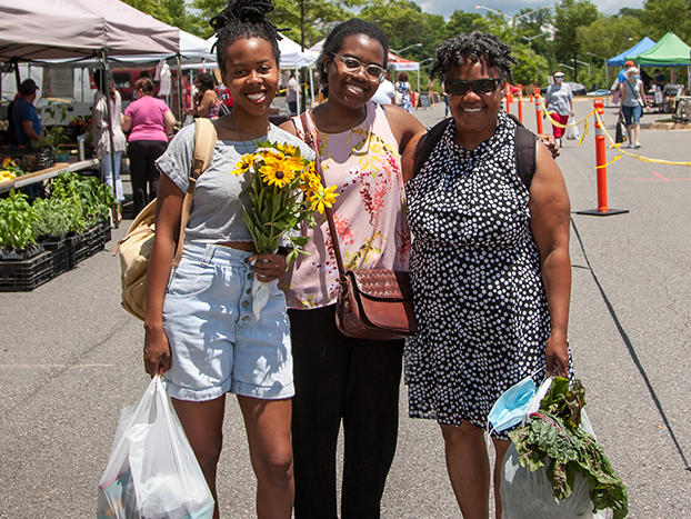 three people holding bags at farmers market