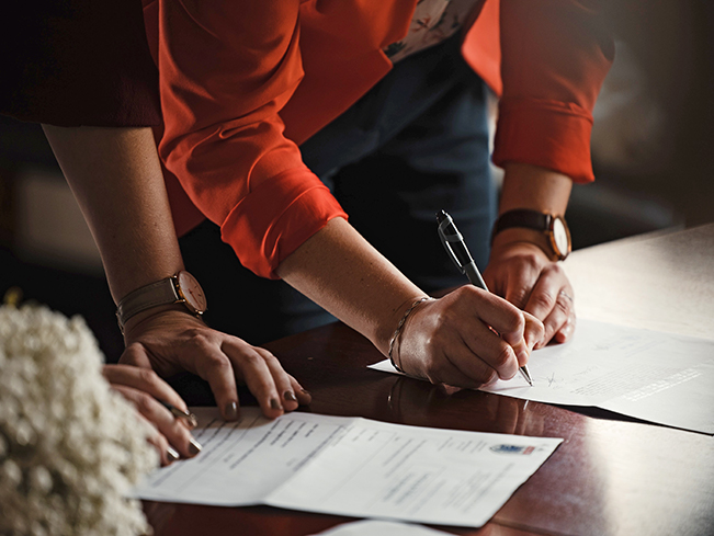 two people signing documents on table