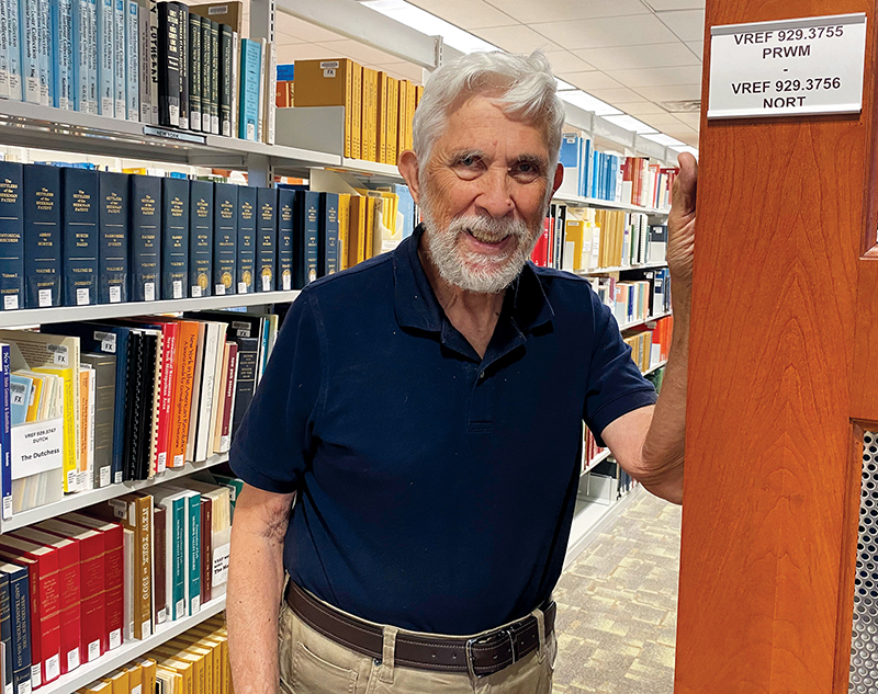Alan Rems standing between two rows of book in the Virginia Room.