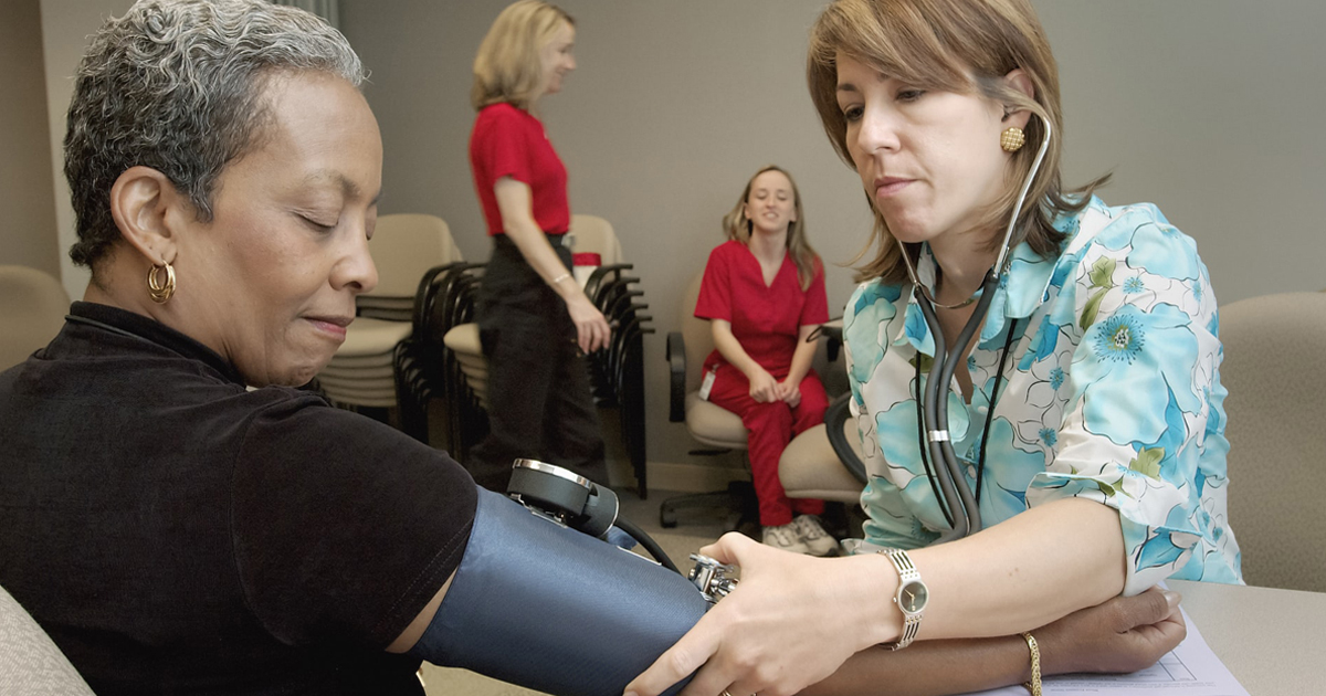 Photo of an older woman getting her blood pressure checked at a health clinic
