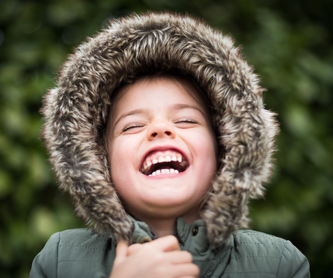 Photo of a little girl in a winter coat laughing