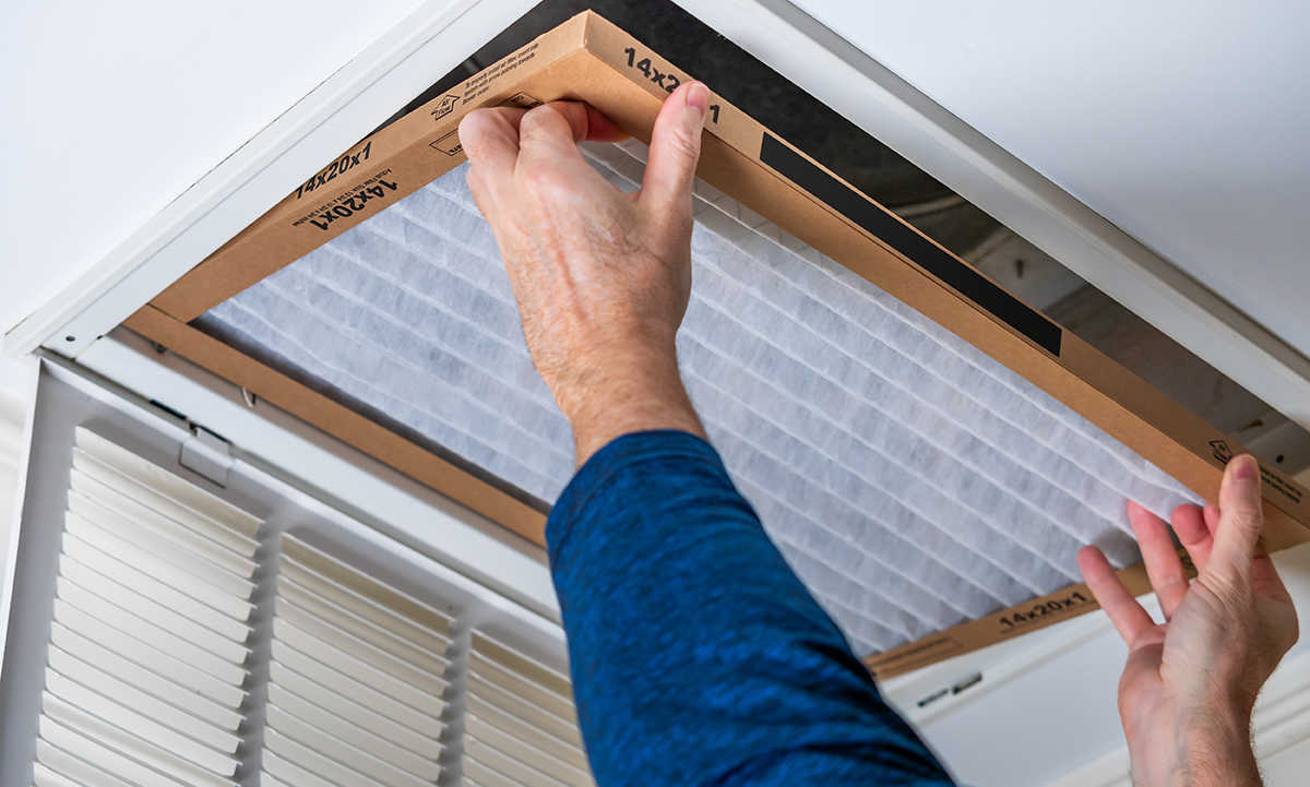 Photo of two hands replacing an air filter.