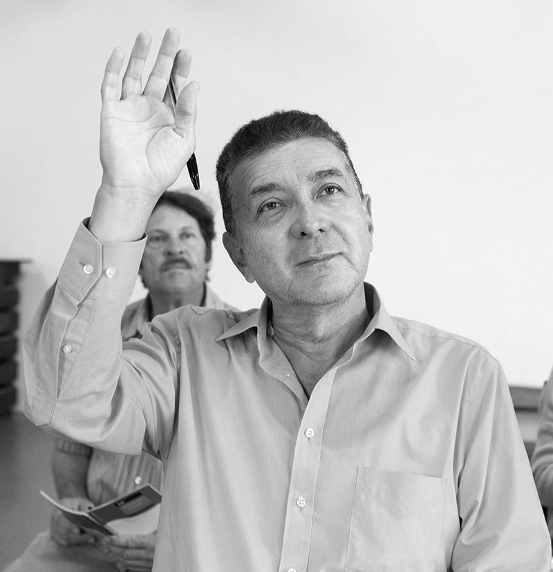 Older man in a classroom raising his hand