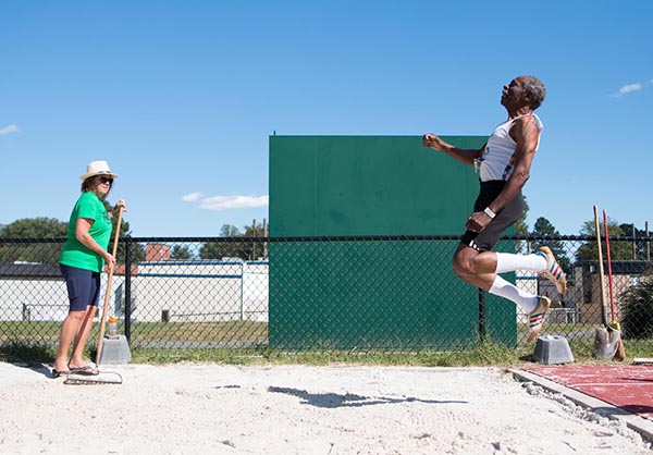 Photo of a man airborne while competing in the running long jump.